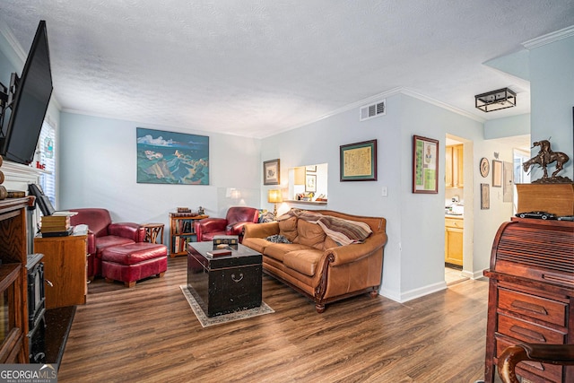 living room with a textured ceiling, ornamental molding, and dark wood-type flooring