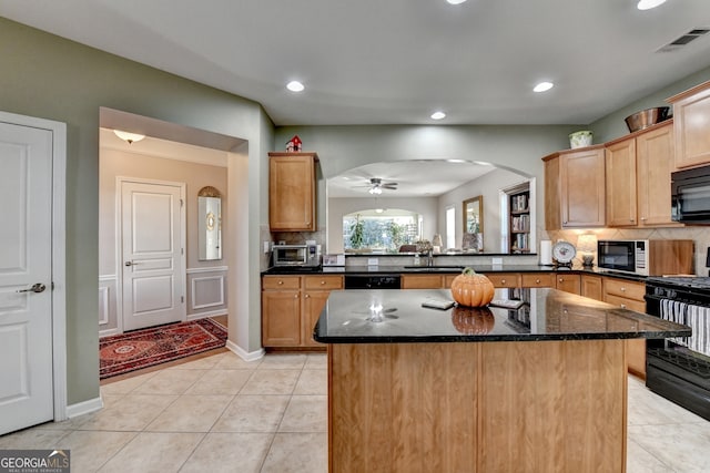 kitchen featuring black appliances, sink, dark stone countertops, a kitchen island, and kitchen peninsula