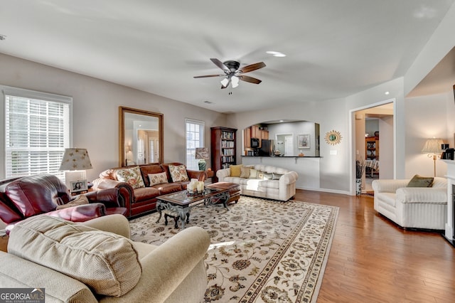 living room featuring wood-type flooring, plenty of natural light, and ceiling fan