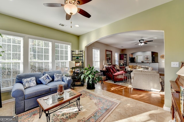 living room with ceiling fan, light wood-type flooring, and a wealth of natural light