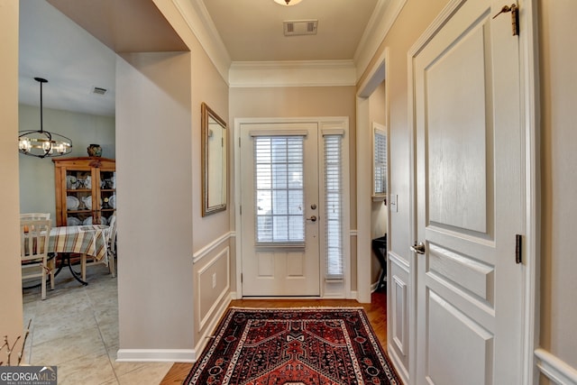 doorway to outside featuring an inviting chandelier, crown molding, and light tile patterned flooring