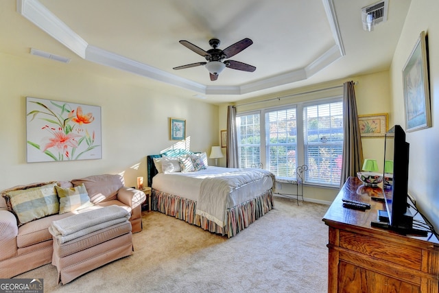 bedroom with a tray ceiling, crown molding, ceiling fan, and light colored carpet