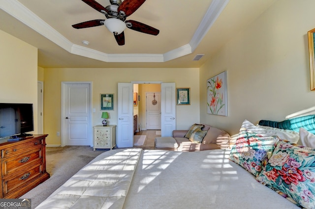 carpeted bedroom featuring ceiling fan, a raised ceiling, and ornamental molding