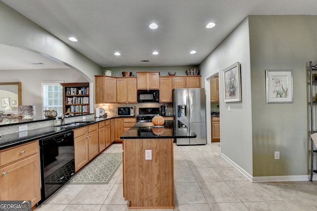 kitchen featuring a center island, sink, dark stone countertops, light tile patterned floors, and black appliances