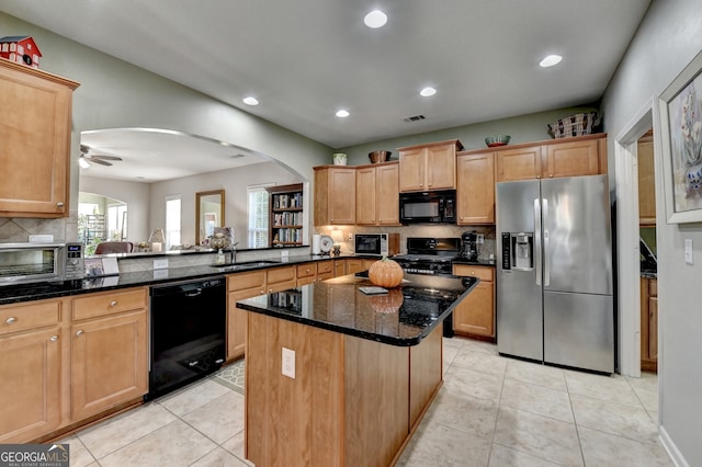 kitchen featuring dark stone counters, black appliances, sink, a kitchen island, and kitchen peninsula