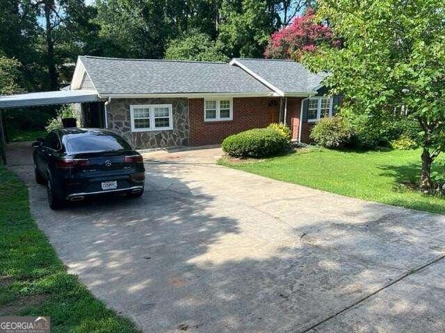 single story home with a front lawn and a carport