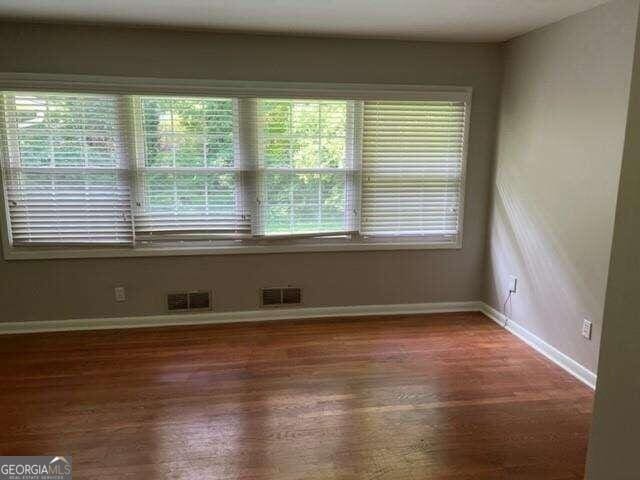 spare room with plenty of natural light and dark wood-type flooring