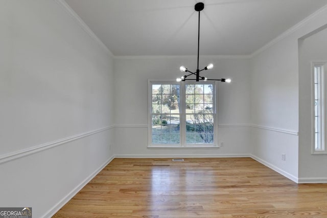 unfurnished dining area with light hardwood / wood-style floors, crown molding, and an inviting chandelier