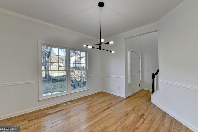 unfurnished dining area with light hardwood / wood-style floors, ornamental molding, and an inviting chandelier