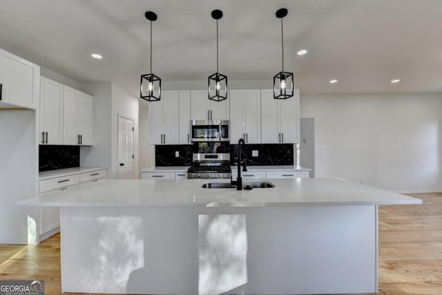 kitchen featuring stainless steel appliances, light hardwood / wood-style flooring, and an island with sink