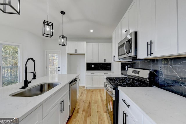 kitchen with white cabinets, pendant lighting, sink, and stainless steel appliances