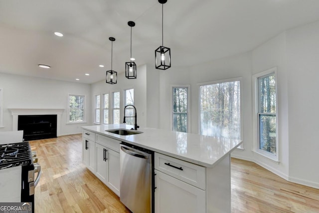 kitchen featuring sink, appliances with stainless steel finishes, decorative light fixtures, white cabinets, and light wood-type flooring