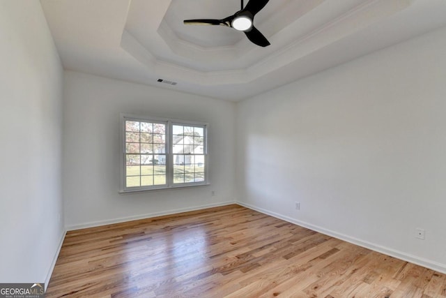 spare room featuring a tray ceiling, light hardwood / wood-style flooring, and ceiling fan