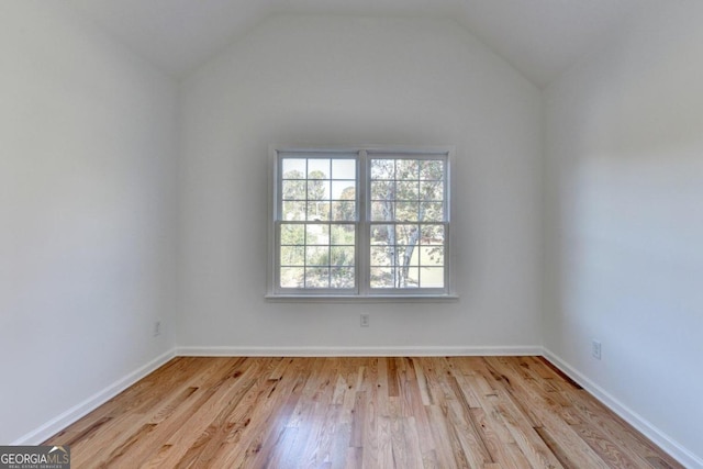 spare room with vaulted ceiling and light hardwood / wood-style flooring