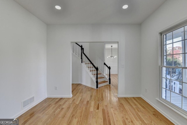 unfurnished room with an inviting chandelier and light wood-type flooring