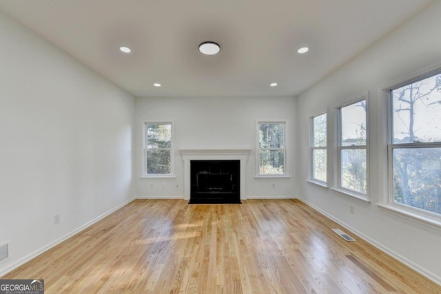 unfurnished living room featuring plenty of natural light and light hardwood / wood-style floors