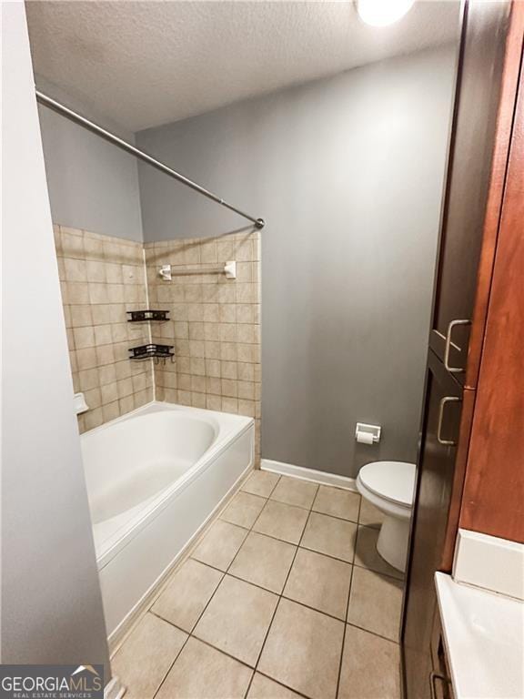 full bathroom featuring tile patterned floors, tiled shower / bath combo, a textured ceiling, and toilet