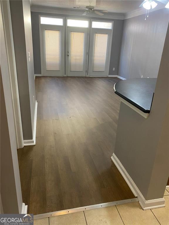 unfurnished living room with ceiling fan, french doors, ornamental molding, and hardwood / wood-style flooring