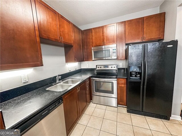 kitchen featuring sink, light tile patterned floors, stainless steel appliances, and a textured ceiling