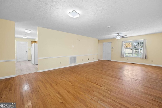 spare room featuring ceiling fan, light hardwood / wood-style flooring, and a textured ceiling