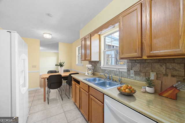 kitchen with backsplash, sink, white refrigerator with ice dispenser, light tile patterned floors, and dishwasher