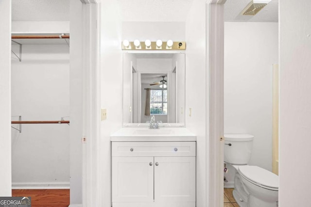 bathroom with vanity, a textured ceiling, ceiling fan, tile patterned flooring, and toilet