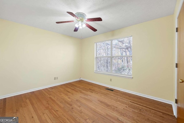 spare room featuring a textured ceiling, light hardwood / wood-style flooring, and ceiling fan