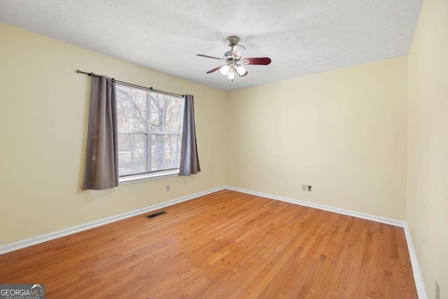 empty room featuring a textured ceiling, light wood-type flooring, and ceiling fan