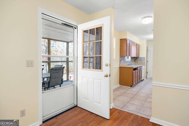 interior space featuring decorative backsplash, light wood-type flooring, and sink