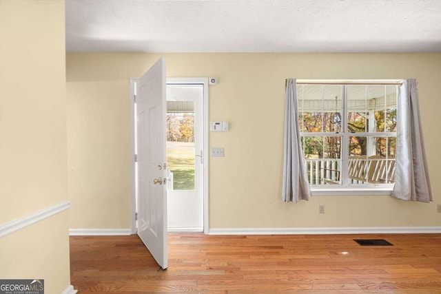 entrance foyer with a textured ceiling and light hardwood / wood-style flooring