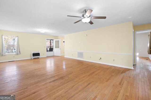 unfurnished living room with a textured ceiling, light hardwood / wood-style floors, heating unit, and ceiling fan