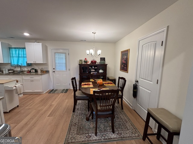 dining space with light hardwood / wood-style floors, sink, and a chandelier