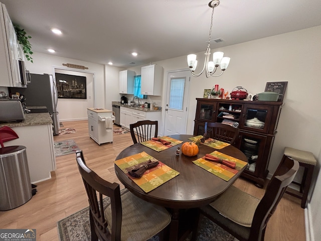 dining area featuring a chandelier, light wood-type flooring, and sink