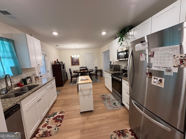 kitchen featuring appliances with stainless steel finishes, sink, white cabinets, a center island, and light hardwood / wood-style floors