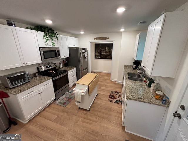 kitchen with sink, light wood-type flooring, appliances with stainless steel finishes, butcher block countertops, and white cabinetry