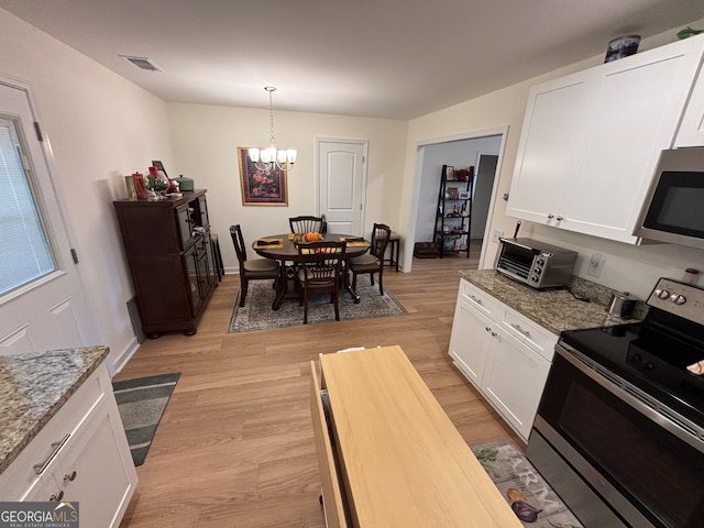 kitchen with white cabinetry, hanging light fixtures, stainless steel appliances, and light wood-type flooring