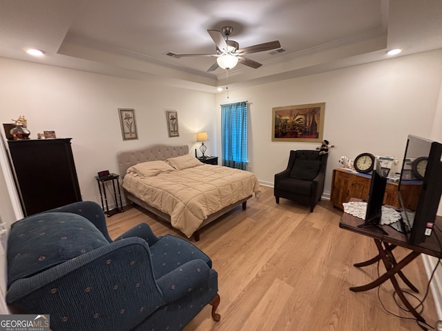 bedroom with a tray ceiling, crown molding, ceiling fan, and light hardwood / wood-style floors