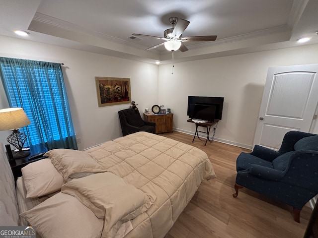 bedroom with light hardwood / wood-style flooring, a raised ceiling, ceiling fan, and crown molding