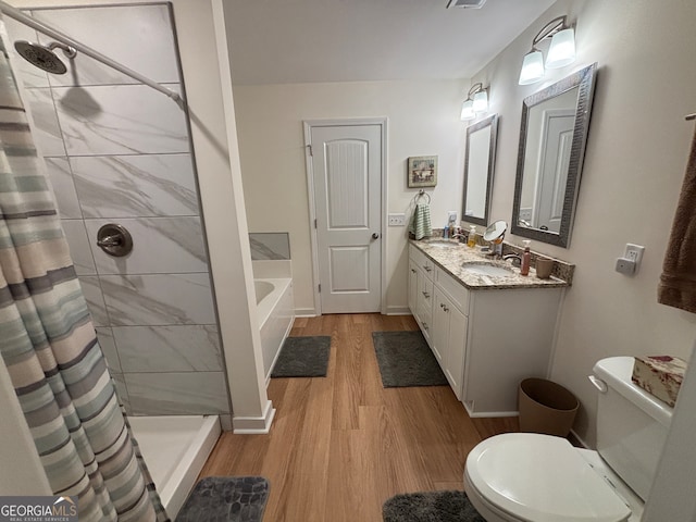 full bathroom with hardwood / wood-style floors, vanity, separate shower and tub, and toilet