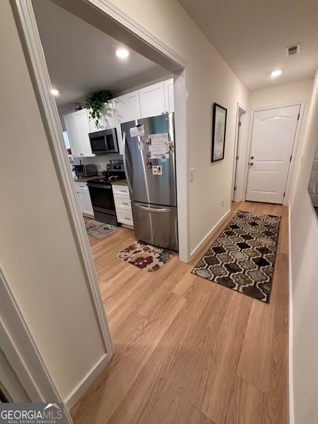 kitchen with white cabinets, light wood-type flooring, and stainless steel appliances