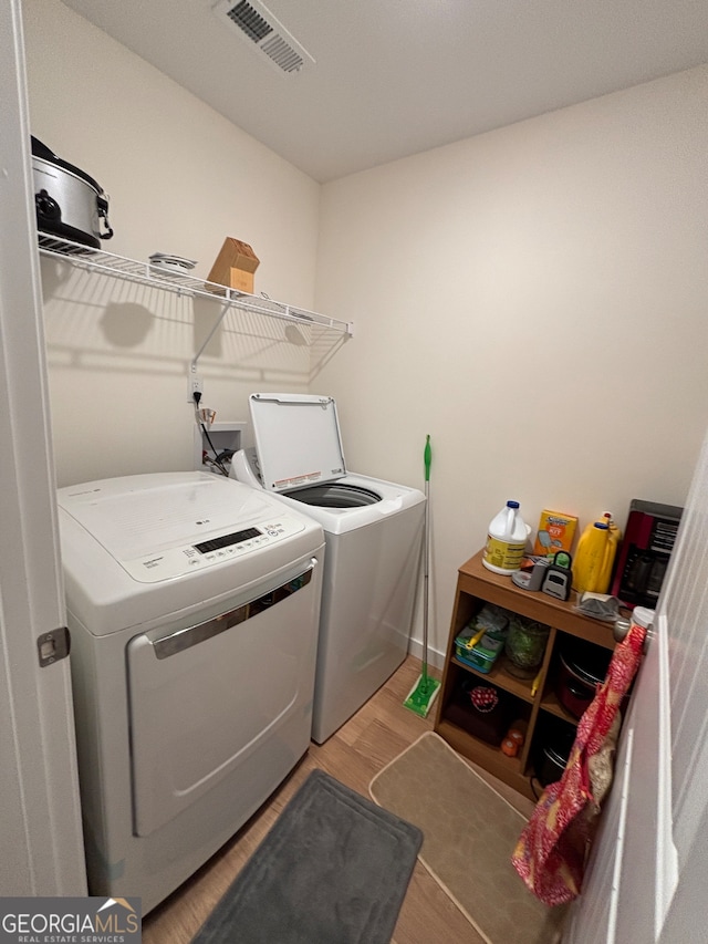 laundry room with washer and dryer and hardwood / wood-style flooring