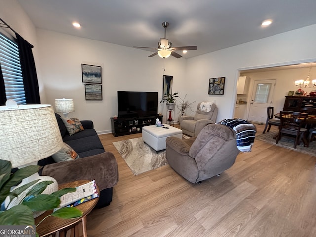 living room featuring ceiling fan with notable chandelier and light hardwood / wood-style floors