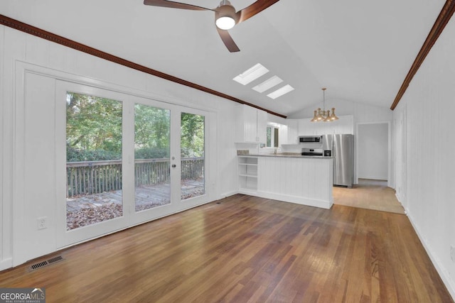 unfurnished living room with light wood-type flooring, ceiling fan with notable chandelier, and vaulted ceiling