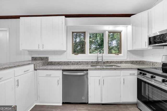 kitchen with light stone countertops, sink, white cabinetry, and stainless steel appliances