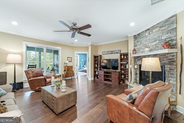 living room featuring a stone fireplace, ceiling fan, dark hardwood / wood-style flooring, and ornamental molding