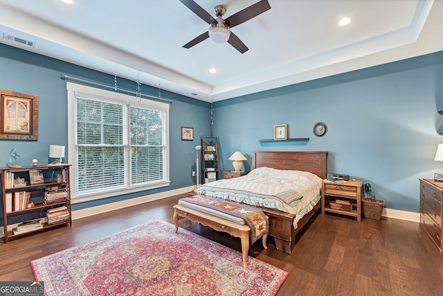 bedroom featuring dark hardwood / wood-style floors, a raised ceiling, and ceiling fan