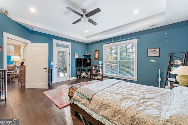 bedroom with a raised ceiling, ceiling fan, and dark wood-type flooring