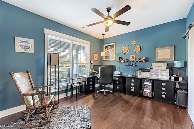 office featuring dark hardwood / wood-style floors, ceiling fan, and a barn door