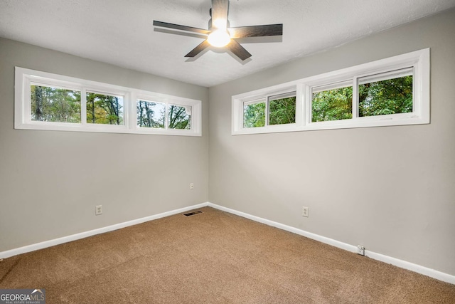 carpeted spare room featuring ceiling fan and a healthy amount of sunlight