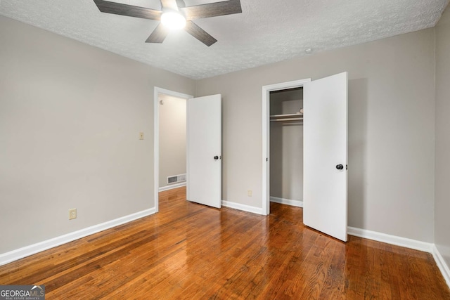 unfurnished bedroom featuring ceiling fan, dark wood-type flooring, and a textured ceiling